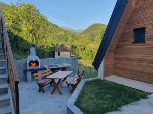 a patio with a grill and a table and benches at KoCHALET Apartment in Crni Vrh