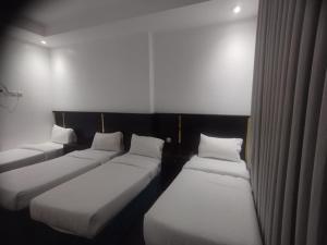 Cette chambre comprend 3 lits avec des draps et des oreillers blancs. dans l'établissement فندق أمل المشاعر, à An Nikāshah