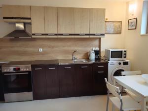 a kitchen with wooden cabinets and a sink and a microwave at Апартамент Мария in Bansko