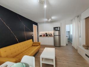 a living room with a yellow couch and a kitchen at Night Day in Padrón