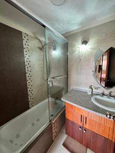 a bathroom with a tub and a sink and a mirror at Lovely 3-bedroom Apt near the Centro de Cuenca in Cuenca