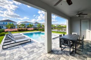eine Terrasse mit Tisch und Stühlen und einem Pool in der Unterkunft Elegant Home Near Disney With Private Pool, Foosball Table, Themed Rooms And Waterpark & Resort Access At Encore Resorts Reunion - 365Sf in Kissimmee