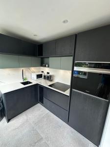 a kitchen with black cabinets and white appliances at Fab-u-Luss in Luss