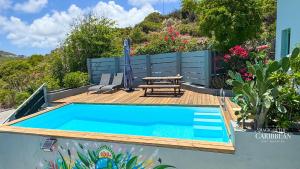 a swimming pool with a picnic table and a wooden deck at VILLA MAGIC - enchanted ocean views & pool - Starlink-cistern-generator in Oyster Pond