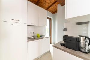 una cucina con armadi bianchi e un bancone con elettrodomestici neri di La Tuscia da Quassù a Montefiascone