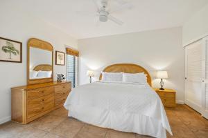 a bedroom with a bed and a dresser and a mirror at Poipu Sands 214 in Koloa