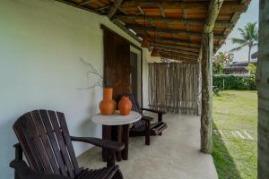 a patio with chairs and a table with vases on it at Evoé Caraíva in Caraíva
