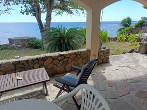 a patio with a table and chairs and the ocean at La PERLE de MOOREA Suite Parentale BORD DE LAGON baie d'OPUNOHU in Orufara