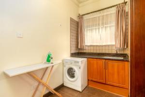a laundry room with a washing machine and a window at Lake Victoria Residence - Stylish 2BR Apartment 10 mins to Airport in Entebbe +13 photos
