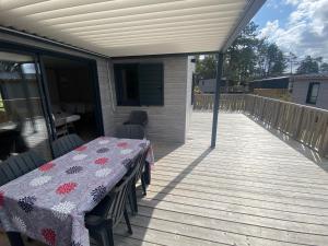 a patio with a table and chairs on a deck at chalet de l'Edune 6 pers beau standing piscine couverte à 150m de la mer wifi inclus in Jullouville-les-Pins