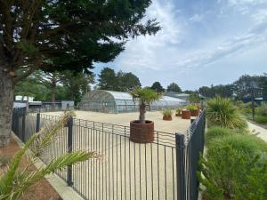 a fence with potted plants in front of a greenhouse at chalet de l'Edune 6 pers beau standing piscine couverte à 150m de la mer wifi inclus in Jullouville-les-Pins