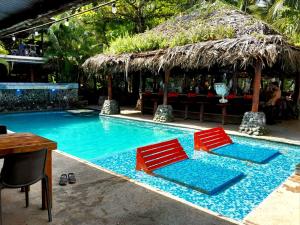 two red chairs sitting next to a swimming pool at Skully's Hostel in La Gruta