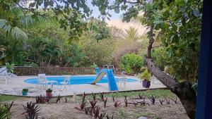 a swimming pool with a slide in a backyard at Casinhas de Pipa in Pipa +2 photos