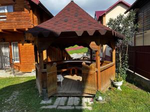 a wooden gazebo in the yard of a house at Затишний будинок in Vorokhta