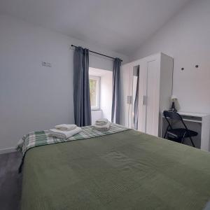 a bedroom with a green bed with two towels on it at Casa das Olarias in Castelo Branco