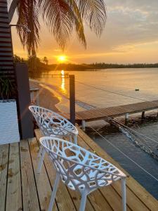 a white chair sitting on a dock with the sunset at Be happy little beach house in Santa Isabel