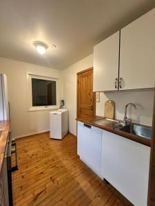 a kitchen with white cabinets and a wooden floor at Charming apartment in Tromsø +6 photos