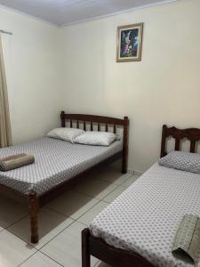 a bedroom with two beds and a picture on the wall at Casa de Campo Sitio com tranquilidade in Cunha