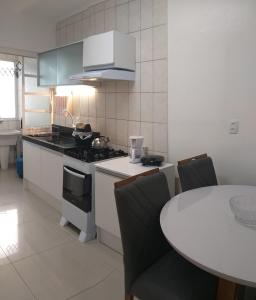a kitchen with a stove and a table with chairs at Ap aconchegante perto de tudo in Caxias do Sul
