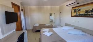 a hotel room with two beds and a flat screen tv at Casablanca Palace Hotel Frutal MG in Frutal +15 photos