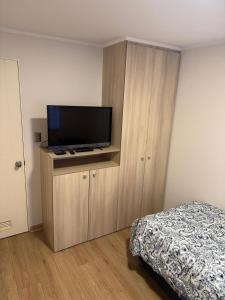 a bedroom with a bed and a flat screen tv at Departamento en Temuco, Parque Oriente in Temuco