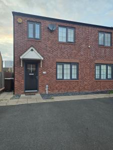 a red brick house with a black door at The Charm in Marston Green