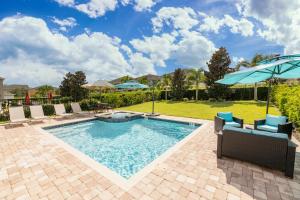 a swimming pool with chairs and an umbrella at Gorgeous Home With Media, Disney Themed Kids Room Near Disney With Waterpark & Resort Access At Encore Resort - 771La in Kissimmee