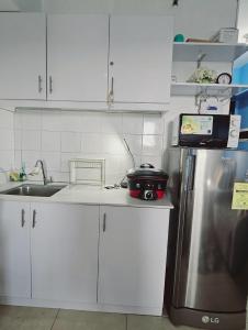 une cuisine avec des armoires blanches et un réfrigérateur en acier inoxydable dans l'établissement Serin West Tagaytay, à Tagaytay