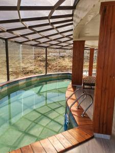 an indoor swimming pool with a wooden deck and a swimming pool at CAR Sport Hotel Titikaka in Huarina