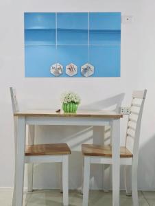 une table à manger blanche avec deux chaises et un vase de fleurs dans l'établissement Serin West Tagaytay, à Tagaytay