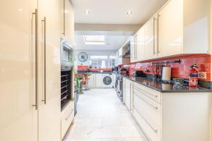 a large kitchen with white cabinets and red walls at Hot Tub and Garden Spacious Unique 3 Bed House in Allesley