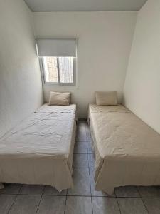 two beds in a small room with a window at Tu lugar tranquilo cerca de todo in San Miguel