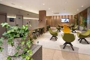 a waiting area in a hospital with green and yellow chairs at Momax Hotel in Marília