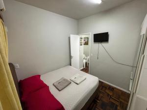 a small bedroom with a bed and a tv at AP Novo, Cama Queen Size Nova no Centro de Blu in Blumenau