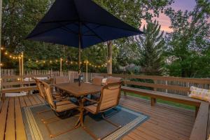 a wooden table and chairs with an umbrella on a deck at Central Family Oasis with Hot Tub & Fenced Yard in Omaha