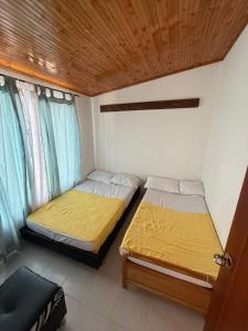two beds in a small room with a wooden ceiling at Hospedaje del Cafe Salento in Salento +10 photos