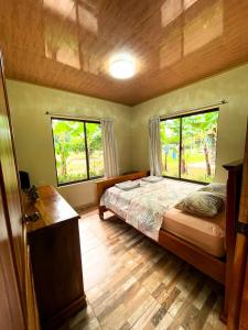 a bedroom with a bed and two windows at Cabañas El Manantial in Esquipulas