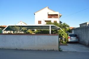 a car parked in a parking lot next to a house at Apartments Pavić in Betina