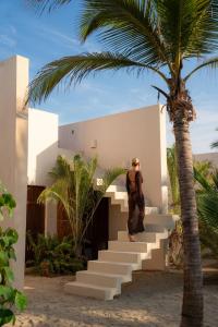 a man standing on the stairs of a house with a palm tree at Casa Yuma, Puerto Escondido in Puerto Escondido +28 photos