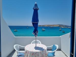 a table with an umbrella on a balcony with the ocean at Glaros Rooms in Koufonisia