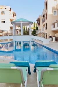 a swimming pool with chairs next to a building at Stylish Studio with Pool Access, Free parking, Paphos center - Work Friendly in Paphos City