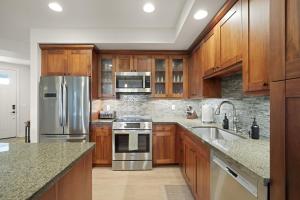 a kitchen with wooden cabinets and stainless steel appliances at Pili Mai 5D condo in Koloa