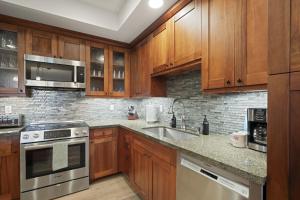 a kitchen with wooden cabinets and stainless steel appliances at Pili Mai 5D condo in Koloa