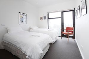 two beds in a room with a chair and a window at Apartment K2 15 AMS Mt Buller in Mount Buller