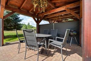 a patio with a table and chairs under a wooden ceiling at Ferienhaus Nationalparkidille in Rechlin