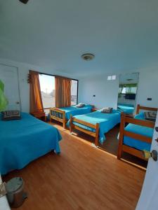 a room with three beds and a mirror at Hostal Pampaloja Antof in Antofagasta