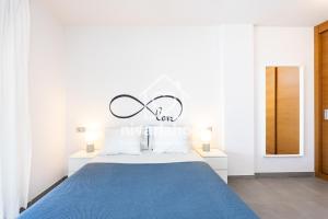 a white bedroom with a blue bed with a sign above it at The Penthouse La Tejita, by Nivariahost in La Tejita +29 photos