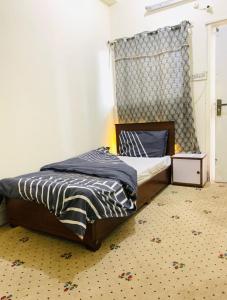 a small bedroom with a bed and a window at Malika Kohsar Hotel Murree in Murree