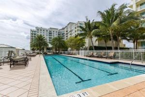 una piscina con sillas y palmeras y un edificio en Beautyful Apartment, Boynton Beach, Casa Costa, FL, en Boynton Beach