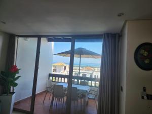 a balcony with a table and an umbrella at BAHIA Sea View Exclusif pour Famille in Cabo Negro